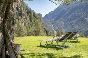 two lawn chairs in a field with mountains in the background at Chalet Heimatjuwel in Längenfeld