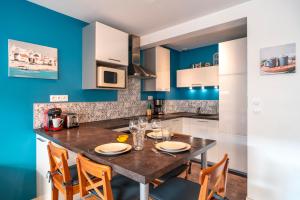 a kitchen with blue walls and a table with chairs at Le Saint-Patern - T3 centre-ville et garage sécurisé in Vannes