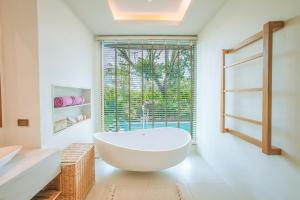 ein Badezimmer mit einer großen weißen Badewanne und einem Fenster in der Unterkunft Luxtalay Khanom Hotel in Khanom