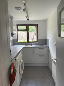 a kitchen with a sink and a washing machine at Cottage Retreat- Sleeps 4 Garden in Sherborne
