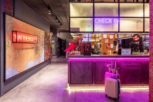 a person with a suitcase sitting in front of a bar at Moxy Lisbon City in Lisbon