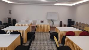 Una sala de conferencias con mesas, sillas y una pizarra. en Oxy Valley Resorts, en Agali