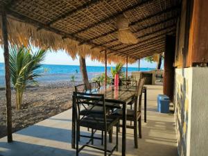 una mesa y sillas en una playa con el océano en Bungalow Soa Majunga, en Mahajanga