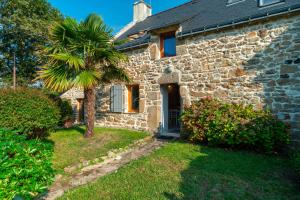 an old stone house with a palm tree in front of it at La Libellule - Charmante maison avec jardin à Séné in Séné