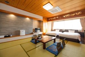 a hotel room with two beds and a table at Hotel Takasago in Kochi