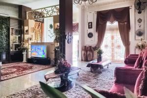 a living room with pink furniture and a large mirror at RedDoorz Syariah at Chilla Guest House Padang in Padang
