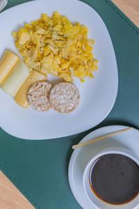 a white plate with cheese and other food on a table at Hotel Lieto in Poços de Caldas