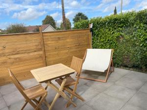 a table and two chairs next to a wooden fence at L'Écrin d'Azurite in Saint-Clair-sur-les-Monts