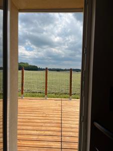 an open door to a deck with a view of a field at L'Écrin d'Azurite in Saint-Clair-sur-les-Monts +6 photos