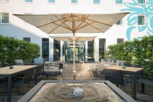 a patio with tables and an umbrella and a fountain at Motel One Hamburg Airport in Hamburg