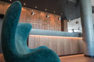a blue chair in a room with a wall at Motel One Hamburg Airport in Hamburg