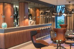 a restaurant with a bar with chairs and tables at Motel One Hamburg Airport in Hamburg