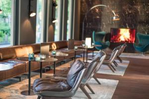a restaurant with tables and chairs and a fireplace at Motel One Hamburg Airport in Hamburg