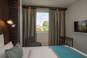 a hotel room with a bed and a window at Motel One Hamburg Airport in Hamburg