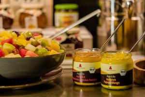 a bowl of fruit next to two jars of honey at Motel One Hamburg Airport in Hamburg