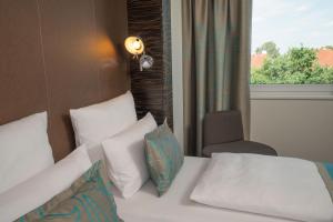 a bedroom with a bed with pillows and a window at Motel One Hamburg Airport in Hamburg