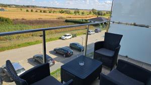 balkon z krzesłami i stołem oraz samochodami na parkingu w obiekcie Apartament Buk w mieście Buk