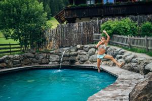 una joven saltando a una piscina en Slow Travel Resort Kirchleitn, en Bad Kleinkirchheim