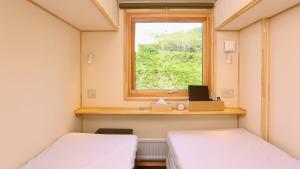 een kamer met twee bedden en een raam bij ホテルカルチャーヴィレッジ in Tomari