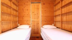 twee bedden in een kamer met houten wanden bij ホテルカルチャーヴィレッジ in Tomari