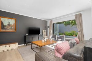 Una sala de estar con un sofá y un televisor. en Uptown Retreat by Host Agents, en Ciudad del Cabo
