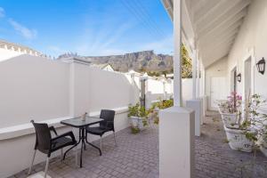 un patio con mesa y sillas con montañas en el fondo en Uptown Retreat by Host Agents, en Ciudad del Cabo