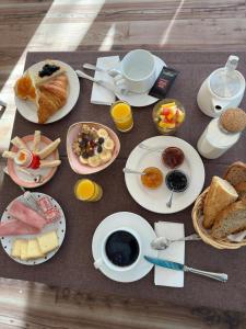 a table with plates of breakfast food on it at Hotel Le Faranchin in Villar-dʼArène
