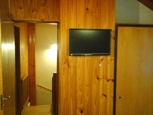 TV de pantalla plana en una pared de madera en una habitación en Cabaña Albar en San Martín de los Andes