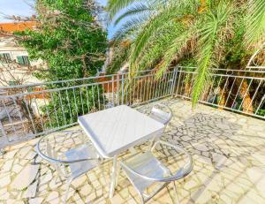 a table and chairs on a patio with palm trees at Apartments Ivan in Novalja