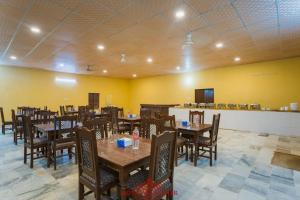 Royal Jaisalmer Resort with Swimming Pool في جيلسامر: مطعم بطاولات وكراسي خشبية في الغرفة