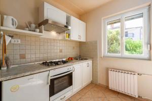 kuchnia z białymi szafkami i oknem w obiekcie Apartment in Porec/Istrien 10034 w Poreču