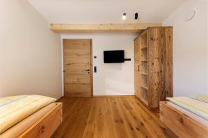 a bedroom with two beds and a tv on the wall at Apartments Schlernheim in Fie allo Sciliar