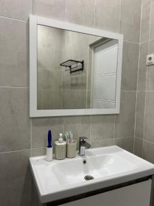 een witte wastafel in een badkamer met een spiegel bij Уютная однушка в центре города in Atıraw