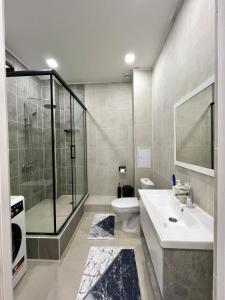 een badkamer met douche, toilet en wastafel bij Уютная однушка в центре города in Atıraw