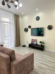 een woonkamer met een bank en een flatscreen-tv bij Уютная однушка в центре города in Atıraw