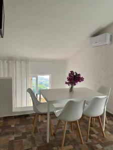 a white dining room table with white chairs and a vase of flowers at Villa Mamia Pool Costa Paradiso in Costa Paradiso