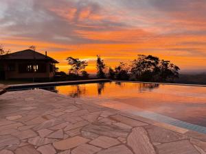 a swimming pool with a sunset in the background at Magnificat Cottage in Cunha