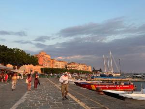 a group of people walking along a dock with boats at Casa Failla - Das Nest am Meer in Siracusa