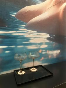 dos copas de vino sentadas en una mesa frente a un cuadro en e-hostel 心斎橋 207, en Osaka