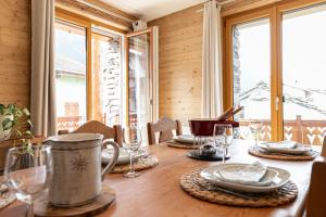 a table with plates and glasses on a table with a window at Appartement La Mottuaz in Bessans +6 photos