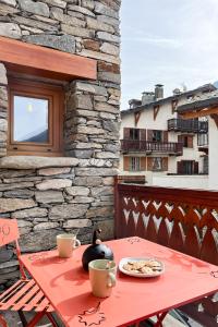 a red table with a plate of food on a patio at Appartement La Mottuaz in Bessans