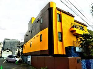 a yellow building with a car parked in front of it at Hotel Unicorn in Nagano