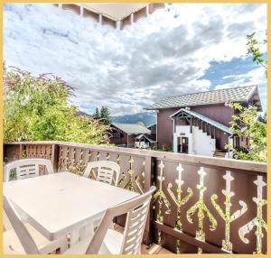 eine Terrasse mit einem weißen Tisch und Stühlen auf dem Balkon in der Unterkunft La ferme I T2 I Les Gets in Les Gets