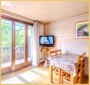 ein Esszimmer mit Tisch und Fernseher in der Unterkunft La ferme I T2 I Les Gets in Les Gets