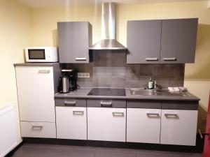 a kitchen with white cabinets and a sink and a microwave at Ferienwohnung Annalena in Gößweinstein
