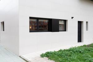 a white house with black windows on the side of it at Apartamento La Gaviota Gijón in Gijón