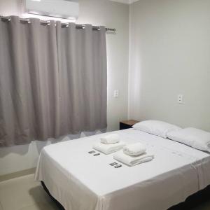 a bedroom with a white bed with towels on it at Casa Palmeira in Primavera do Leste