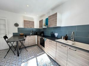 - une cuisine avec des placards en bois, une table et un évier dans l'établissement 1007 Ker Jean Louis - Maison 7p à 300m de la plage, à Pléneuf-Val-André