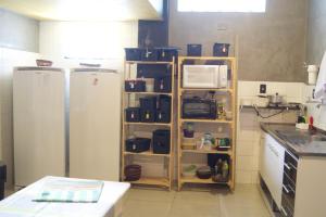 a kitchen with two refrigerators and a shelf with appliances at Hotel Econômico ao lado do Metrô in São Paulo