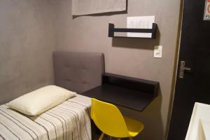 a small room with a bed and a yellow chair at Hotel Econômico ao lado do Metrô in São Paulo